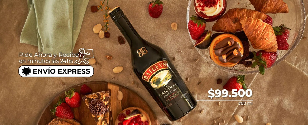 Botella de crema de whisky Baileys Original con postres y fresas